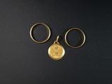 deux bagues en or et une pièce d'or sur un fond noir