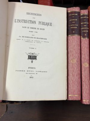 Plusieurs livres sont empilés sur une étagère dans une bibliothèque.