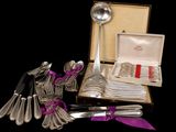 a bunch of silverware in a box with a purple ribbon