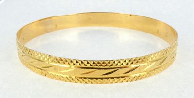 a close up of a gold bracelet on a white surface