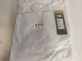 une chemise blanche posée sur une table blanche, avec une étiquette dessus
