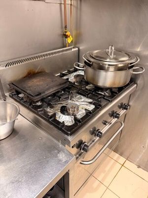une cuisinière sur laquelle sont posées des casseroles et des poêles, dans une cuisine