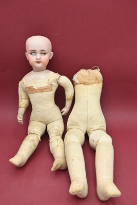 pair of old wooden dolls sitting next to each other on a red surface