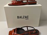 Chaussures Balzac orange et noires, avec une boîte posée sur un fond blanc