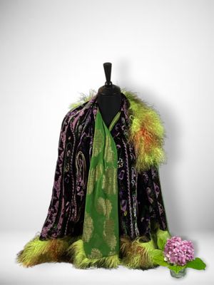 a black and green coat with a green scarf and a pink flower