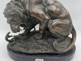 statue d'un lion perché sur un rocher, tenant un serpent dans la gueule