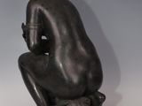 statue of a woman sitting on a rock with her hands on her knees