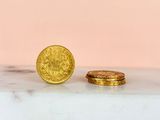 two gold coins sitting on top of a marble counter top