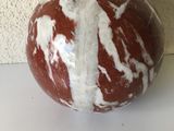 une boule en marbre rouge et blanche posée sur une table