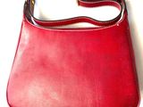 red leather purse on white background with strap around it