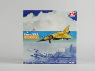 La boîte contient une maquette d'un avion de chasse survolant une ville.