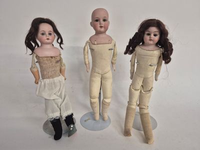 three dolls standing next to each other on a white surface