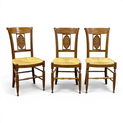 three wooden chairs with wicker seats and a cane back