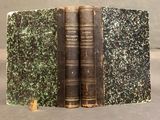 two old books sitting on top of each other on a table