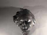 a black and white photo of a statue of a man ' s head in a bathtub