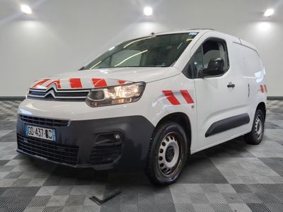 une camionnette Citroën rayée de rouge et de blanc, garée dans un garage