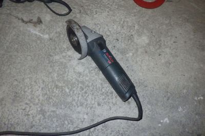 un petit outil électrique posé par terre à côté d'une paire de ciseaux
