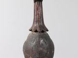 an old wooden object hanging from a rope on a white wall