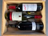 three bottles of wine in a wooden box on a table