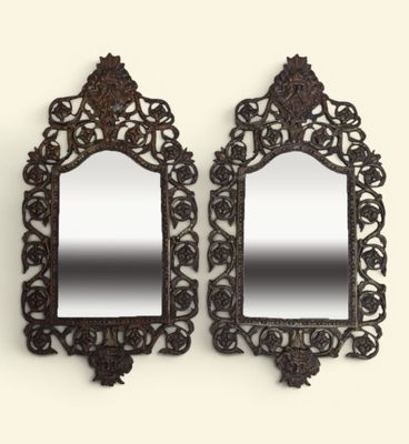 une paire de miroirs richement sculptés accrochés à un mur blanc