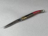 un petit couteau au manche rouge posé sur une table