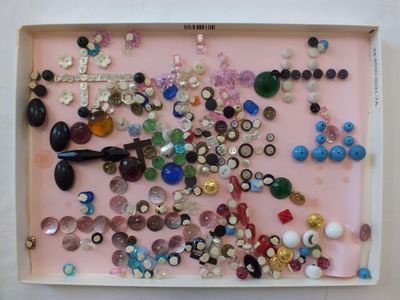 une photo d'un plateau rose rempli de boutons et de perles