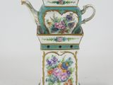 a small teapot with a flowered design on it
