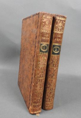two old books sitting on top of each other on a gray surface