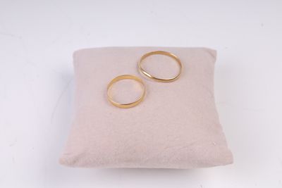 une paire d'alliances en or posées sur un coussin, sur une surface blanche