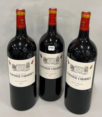 trois bouteilles de vin rouge sont alignées sur une surface blanche