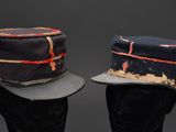pair of military hats on a mannequin head on a black background