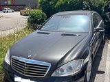 a black car parked in a parking lot next to a hedge