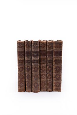 six old books stacked on top of each other on a white surface