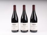 trois bouteilles de vin rouge sont alignées sur une surface blanche