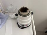 a white blender sitting on top of a counter next to a cup