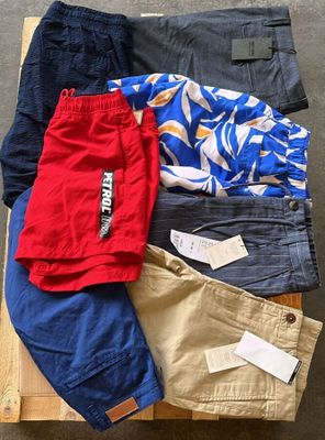 Plusieurs paires de pantalons pour hommes sont disposées sur une caisse en bois