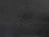 the back of a black jacket with a small hole in it