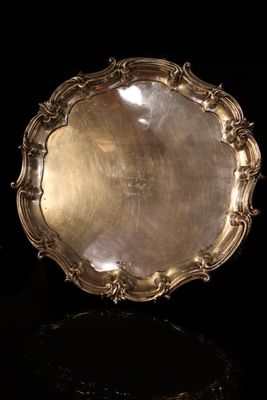 an antique silver plate on a black surface with a black background