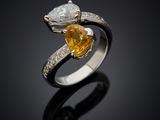 a yellow sapphire and diamond ring on a black surface