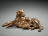 bronze sculpture of a dog laying down on a gray surface