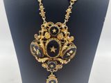 a black and gold necklace on a mannequin display