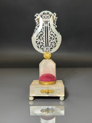 a white and gold clock with a red cushion on it