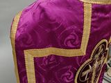 a purple and gold vest with a cross on it