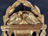 a gold clock with two birds sitting on top of it