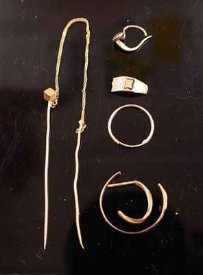 quelques bagues en or et d'autres bijoux sont posés sur une surface noire