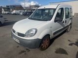 La petite camionnette blanche est garée sur un parking, à côté d'autres voitures.