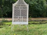 a white bird cage sitting on top of a lush green field