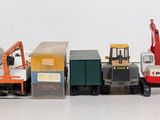 several toy trucks are lined up in a row on a white surface