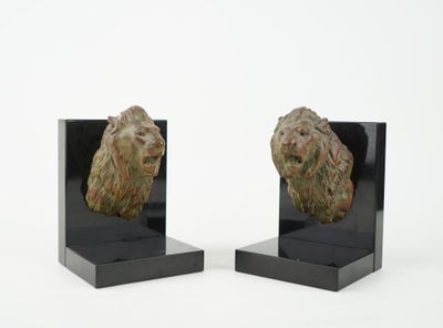 pair of art deco bookends of a lion head on a black marble base