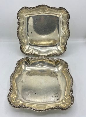 une paire de plateaux en métal argenté posés sur une surface blanche